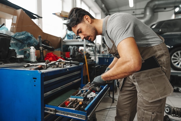 Técnico masculino parado cerca de la mesa de herramientas en el servicio de automóviles