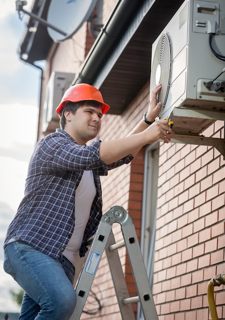 Técnico masculino que repara el sistema de aire acondicionado exterior