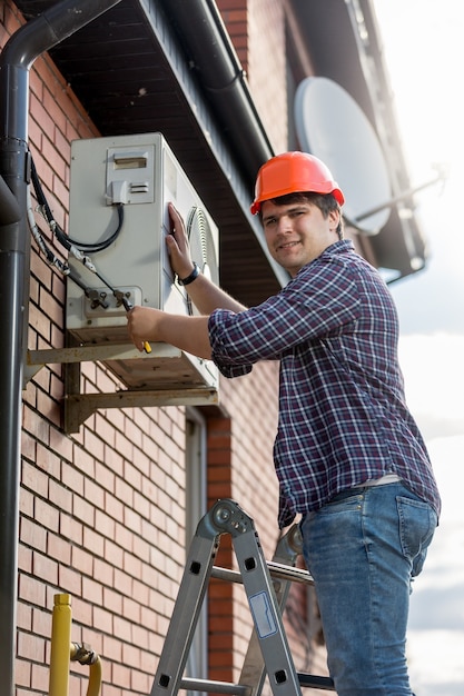 Técnico masculino que repara el sistema de aire acondicionado exterior