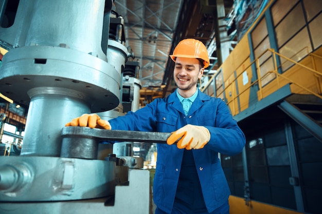 Foto técnico masculino en uniforme y casco trabaja en fábrica