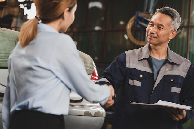 Un técnico mecánico le da la mano al cliente después de terminar de revisar el automóvil en el garaje. Dos personas se dan la mano para un trabajo en el centro profesional de servicio de reparación de automóviles.