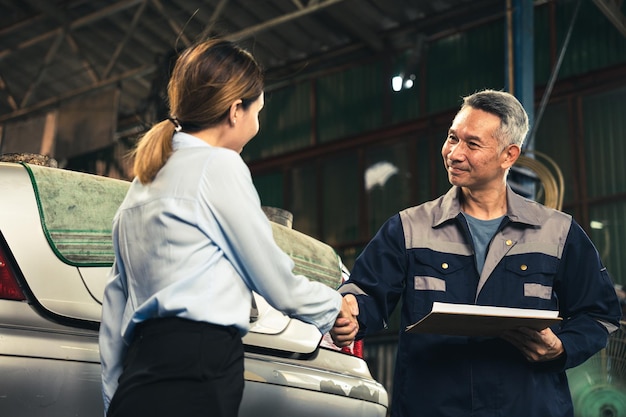 Técnico mecánico haciendo un trato de apretón de manos con el cliente comercial en el taller de servicio de garaje de automóviles ocupación para reparación de mantenimiento de automóviles trabajador de la industria adulta saludo para el acuerdo del cliente