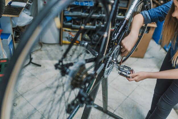 Técnico mujer fijación bicicleta en taller de reparación