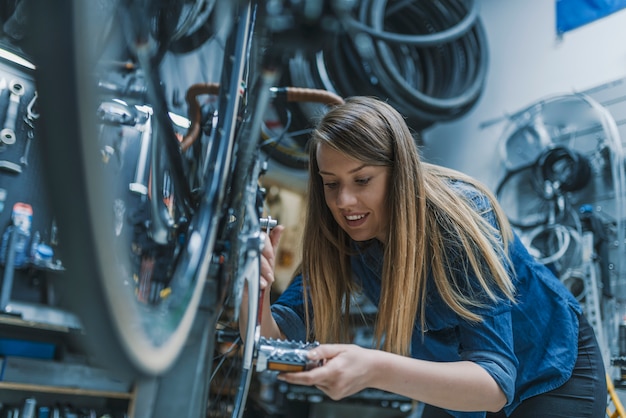 Técnico mujer fijación bicicleta en taller de reparación