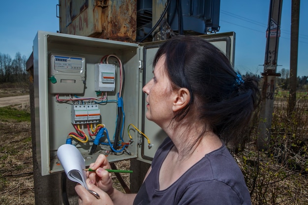 Foto técnico de la mujer leyendo el contador de electricidad para comprobar el consumo.