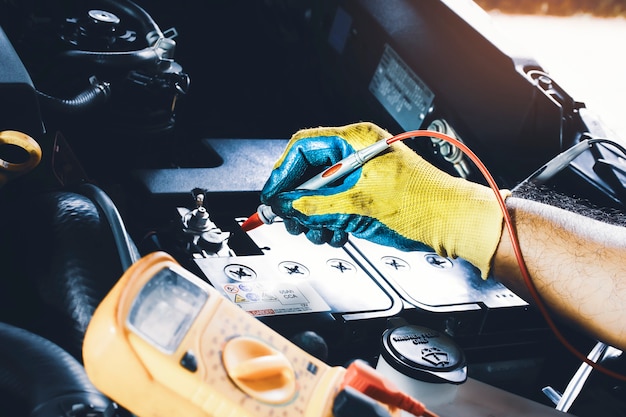 Técnico para verificação de tensão estável da bateria do carro com sonda de multímetro digital