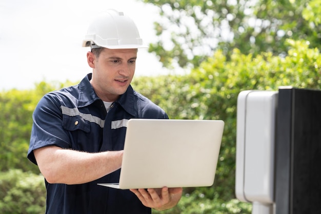 Técnico qualificado trabalhando na instalação da estação de carregamento de EV em casa, solucionando problemas e configurando o sistema de carregamento com laptop para EV em casa Synchronos