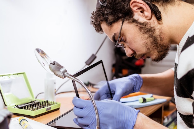 Foto técnico que cambia la pantalla táctil de la tableta