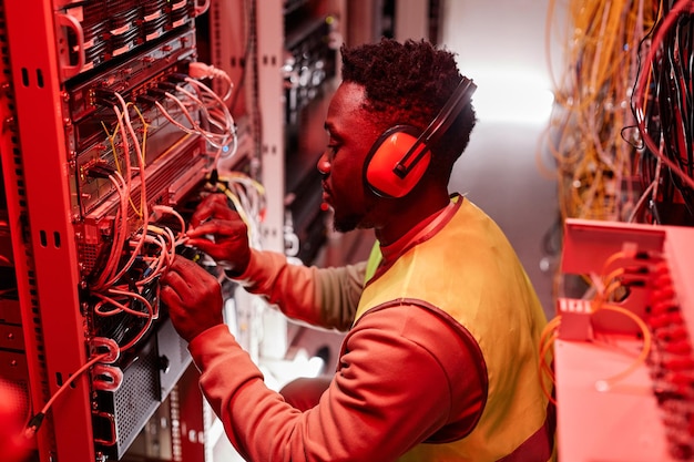 Técnico que configura la red en la sala de servidores con luces de neón rojas