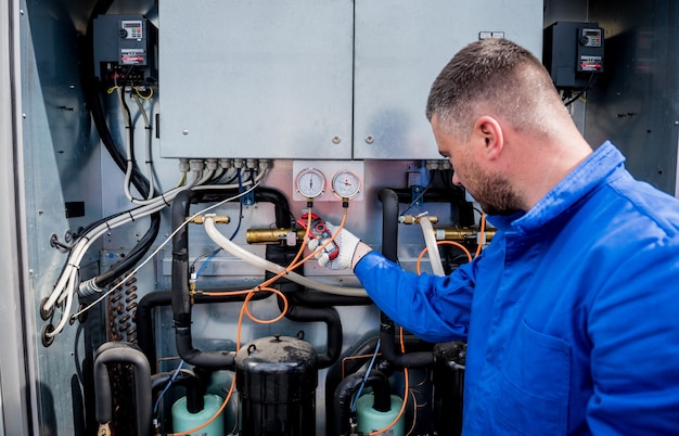 El técnico que controla las líneas eléctricas del intercambiador de calor con pinzas amperimétricas