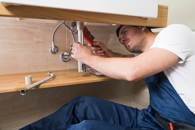 Foto técnico que repara el fregadero en el baño