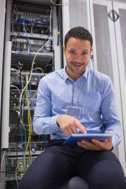 Foto técnico que trabaja en la pc de la tableta al lado de los servidores