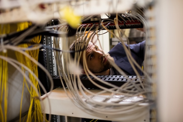 Técnico que verifica cabos em um servidor montado em rack