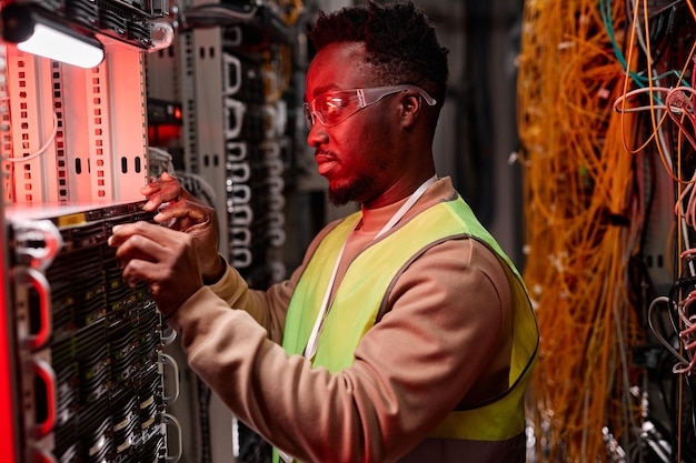 Técnico de red inspeccionando servidores en el centro de datos luz de neón roja