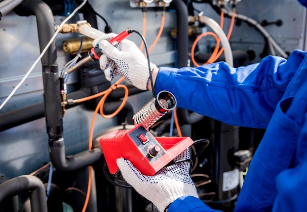 El técnico repara los sensores de temperatura electrónicos con un soldador electrónico.