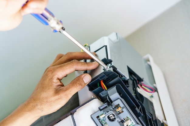 Técnico de reparación de aire acondicionado con destornillador, instale los cables eléctricos del aire acondicionado