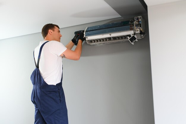 Técnico en reparación de aire acondicionado en pared.