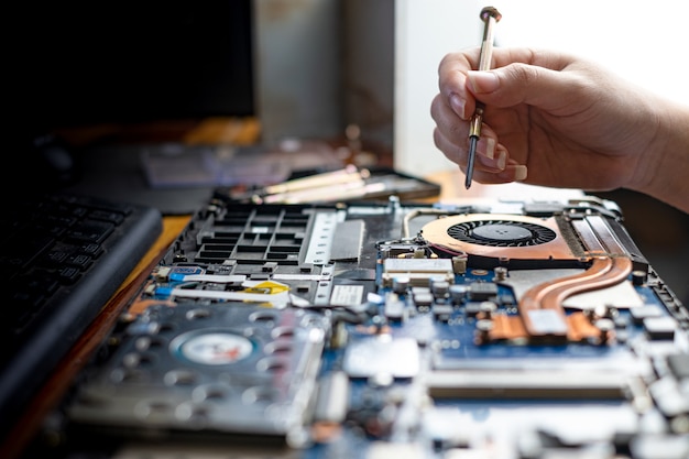 Técnico reparando computador portátil quebrado com chave de fenda