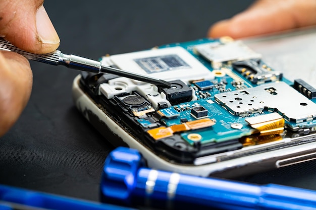 Técnico reparando dentro do telefone celular por circuito integrado de ferro de solda o conceito de tecnologia de hardware de dados