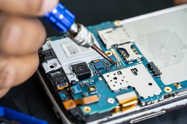 Técnico reparando dentro do telefone celular por circuito integrado de ferro de solda o conceito de tecnologia de hardware de dados