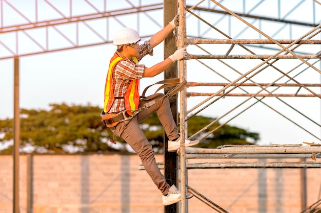 Foto técnico en ropa de seguridad está subiendo andamios