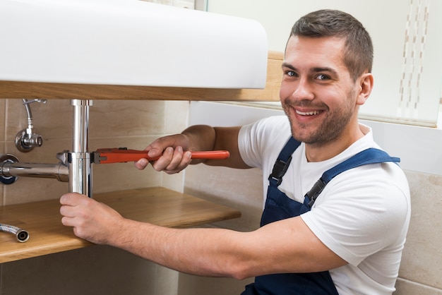 Técnico sanitário adulto sorridente com chave