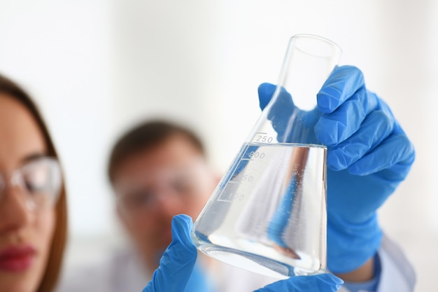 Foto técnico sostiene en brazos en botella de muestra de guantes protectores