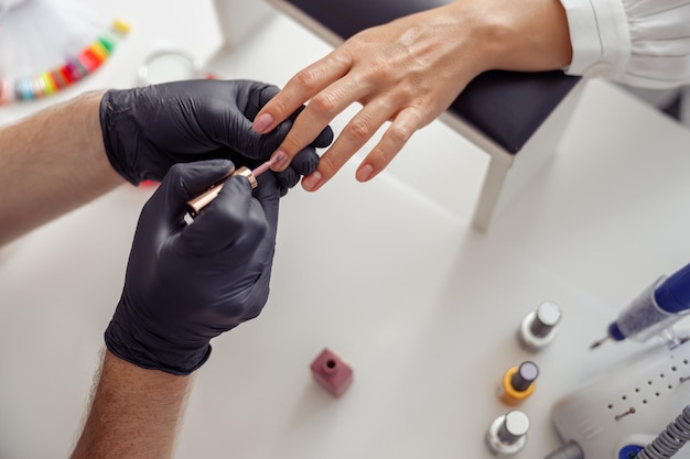 Técnico de uñas aplicando esmalte a las uñas de los clientes en el salón