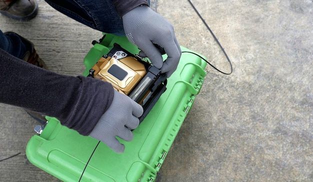 Técnico usa máquina de emenda de fusão para cabo de fibra óptica de emenda em caixa verde na rua