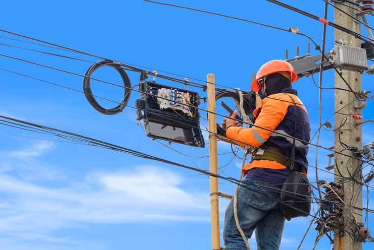 Foto técnico usando smartphone durante a instalação do sistema de internet de fibra óptica no poste elétrico