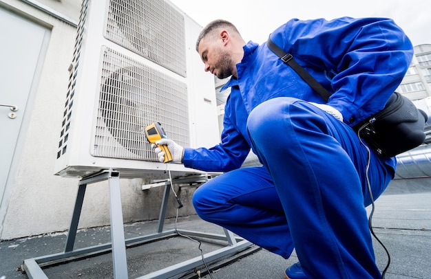 El técnico utiliza un termómetro infrarrojo de imágenes térmicas para comprobar el intercambiador de calor de la unidad de condensación