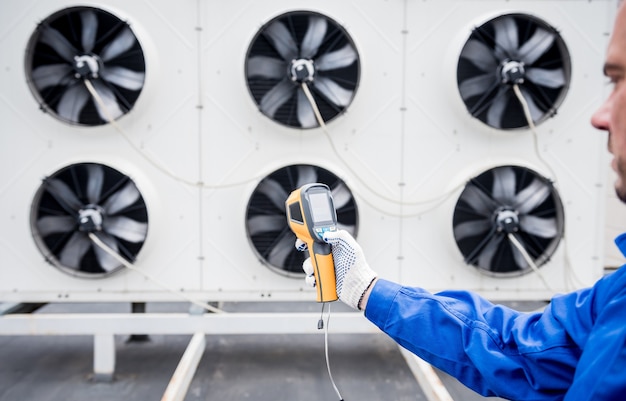 Foto el técnico utiliza un termómetro infrarrojo de imágenes térmicas para comprobar el intercambiador de calor de la unidad de condensación