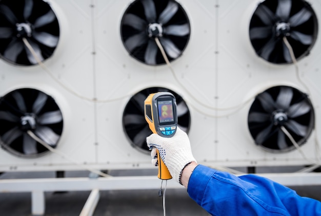 Foto el técnico utiliza un termómetro infrarrojo de imágenes térmicas para comprobar el intercambiador de calor de la unidad de condensación