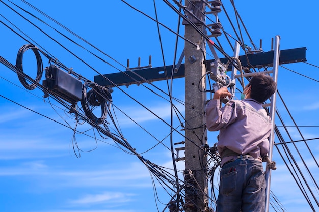 Técnico verificando e renovando o sistema de TV a cabo digital para amplificar sinais de TV em poste elétrico