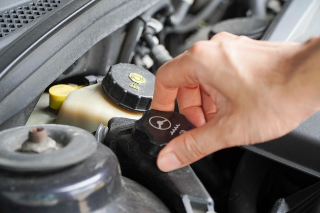 Foto técnicos asiáticos inspeccionan el aceite de la dirección asistida del automóvil para el cuidado del compartimiento del motor y el concepto de servicio básico del vehículo y el sistema de frenos