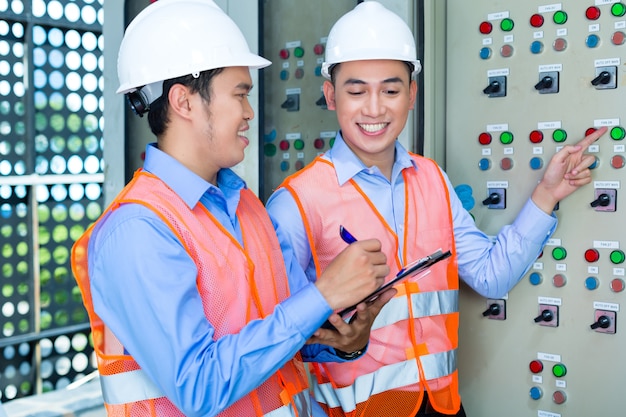 Técnicos asiáticos no painel no canteiro de obras