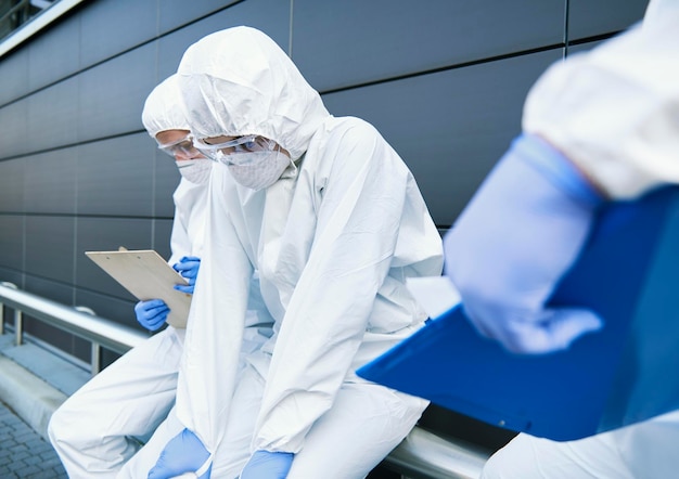 Técnicos cansados trabajando con trajes de protección