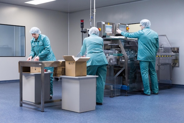 Técnicos farmacêuticos trabalham em condições de trabalho estéreis na fábrica farmacêutica cientistas vestindo roupas de proteção