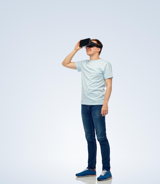 Tecnología 3d, realidad virtual, entretenimiento, ciberespacio y concepto de personas: joven feliz con auriculares de realidad virtual o gafas 3d mirando algo