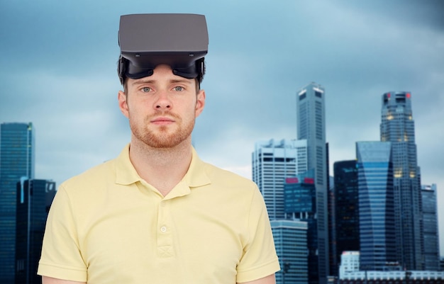 Tecnología 3D, realidad virtual, entretenimiento y concepto de personas: joven con auriculares de realidad virtual o gafas 3D sobre el fondo de los rascacielos de la ciudad de Singapur