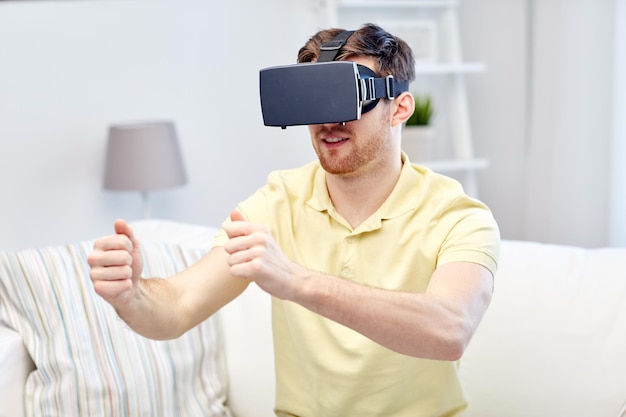 Tecnología 3d, realidad virtual, juegos, entretenimiento y concepto de personas: joven con auriculares de realidad virtual o gafas 3d jugando videojuegos de carreras en casa