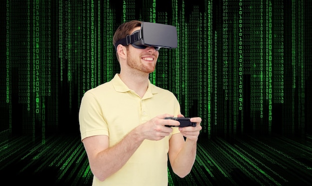 tecnologia 3d, realidade virtual, entretenimento e conceito de pessoas - jovem feliz com fone de ouvido de realidade virtual ou óculos 3d jogando com gamepad de controlador de jogo sobre fundo de código binário