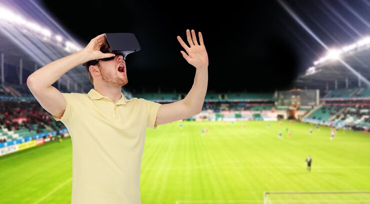 Foto tecnologia 3d, realidade virtual, esporte, entretenimento e conceito de pessoas - jovem feliz com fone de ouvido de realidade virtual ou óculos 3d jogando jogo sobre campo de futebol no fundo do estádio