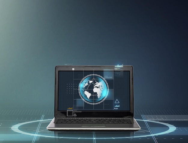 tecnología y concepto de red: computadora portátil con globo terráqueo en pantalla sobre fondo gris