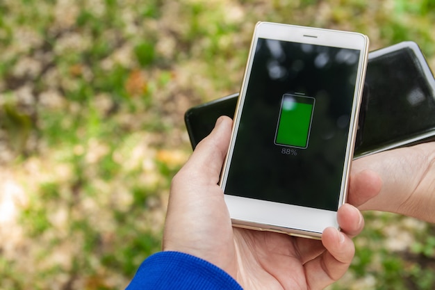 Tecnologia de compartilhamento de carga sem fio da bateria do telefone. as pessoas compartilham sua carga de smartphone sem fio no parque.