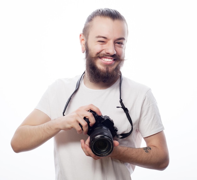 Tecnologia de estilo de vida e conceito de viagem homem barbudo vestindo camiseta branca com uma câmera digital isolada em um fundo branco