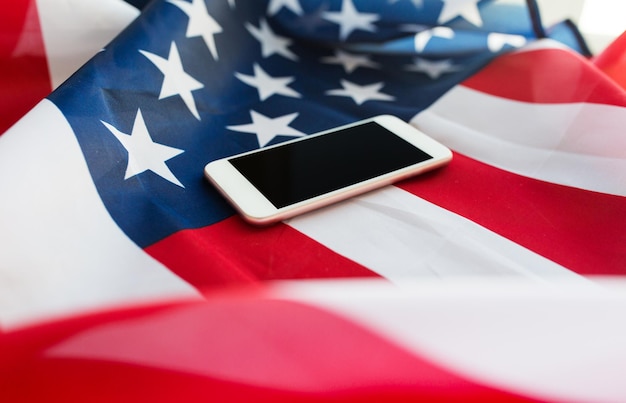 Foto tecnologia, dia da independência americana, conceito de patriotismo e nacionalismo - close-up do computador smartphone na bandeira americana