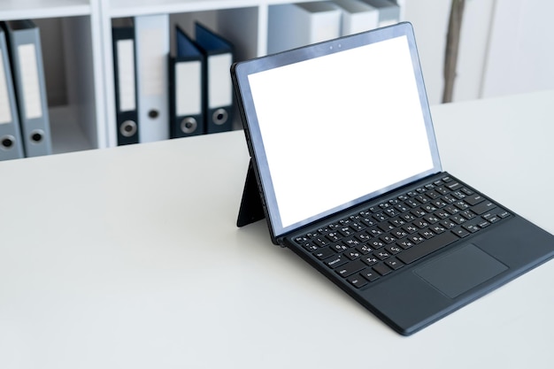 La tecnología digital de la maqueta de la computadora de trabajo de oficina abrió la computadora portátil con la pantalla en blanco en el escritorio blanco