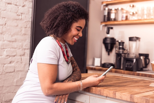 Tecnologia digital. mulher alegre e feliz usando seu smartphone enquanto está sentado no café