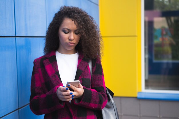 Tecnologia e comunicação. mulher adolescente infeliz enviando mensagens de texto no celular usando smartphone lendo sms no azul